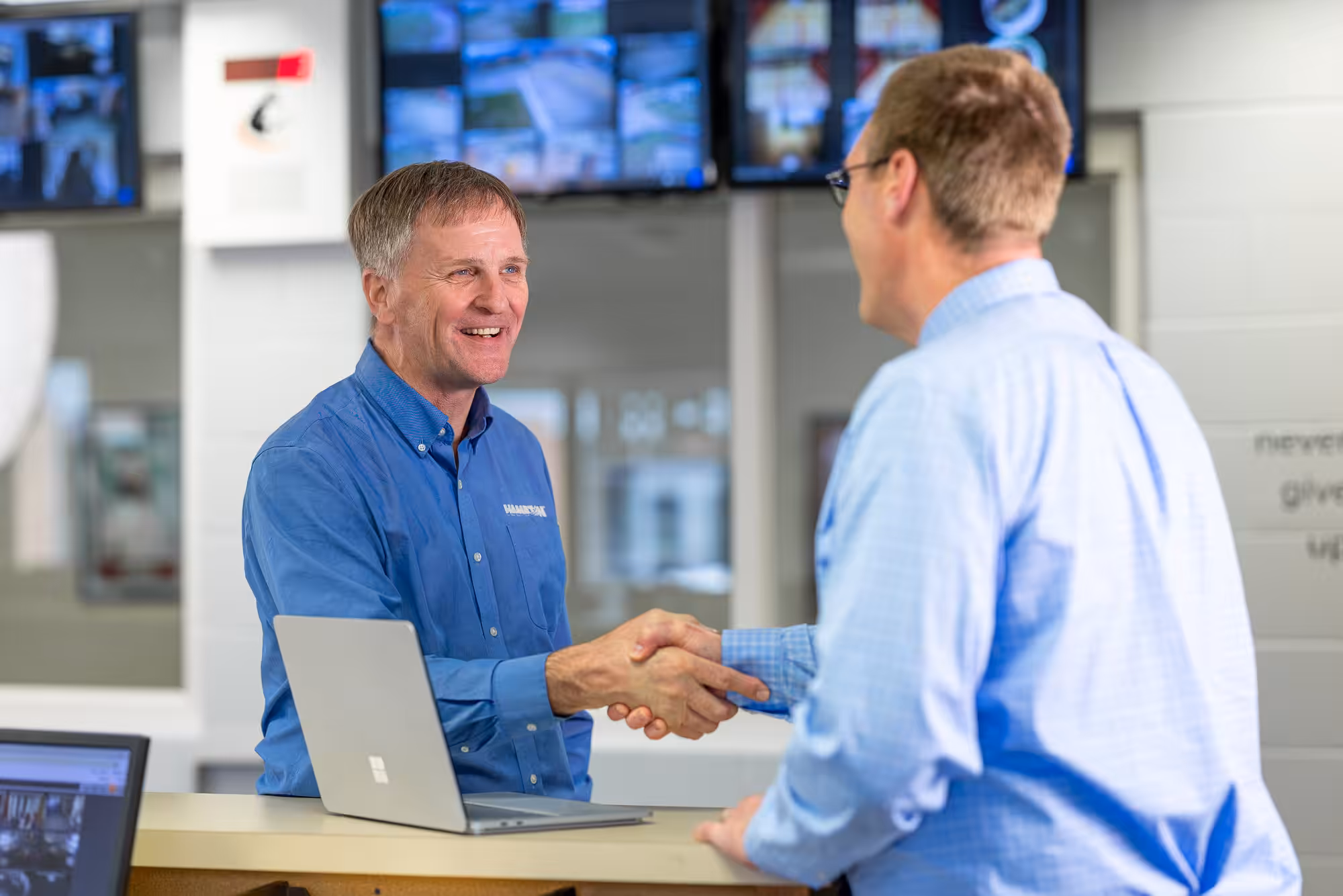 Hamilton Salesman shaking hands with a school principle with hamilton security system in the background
