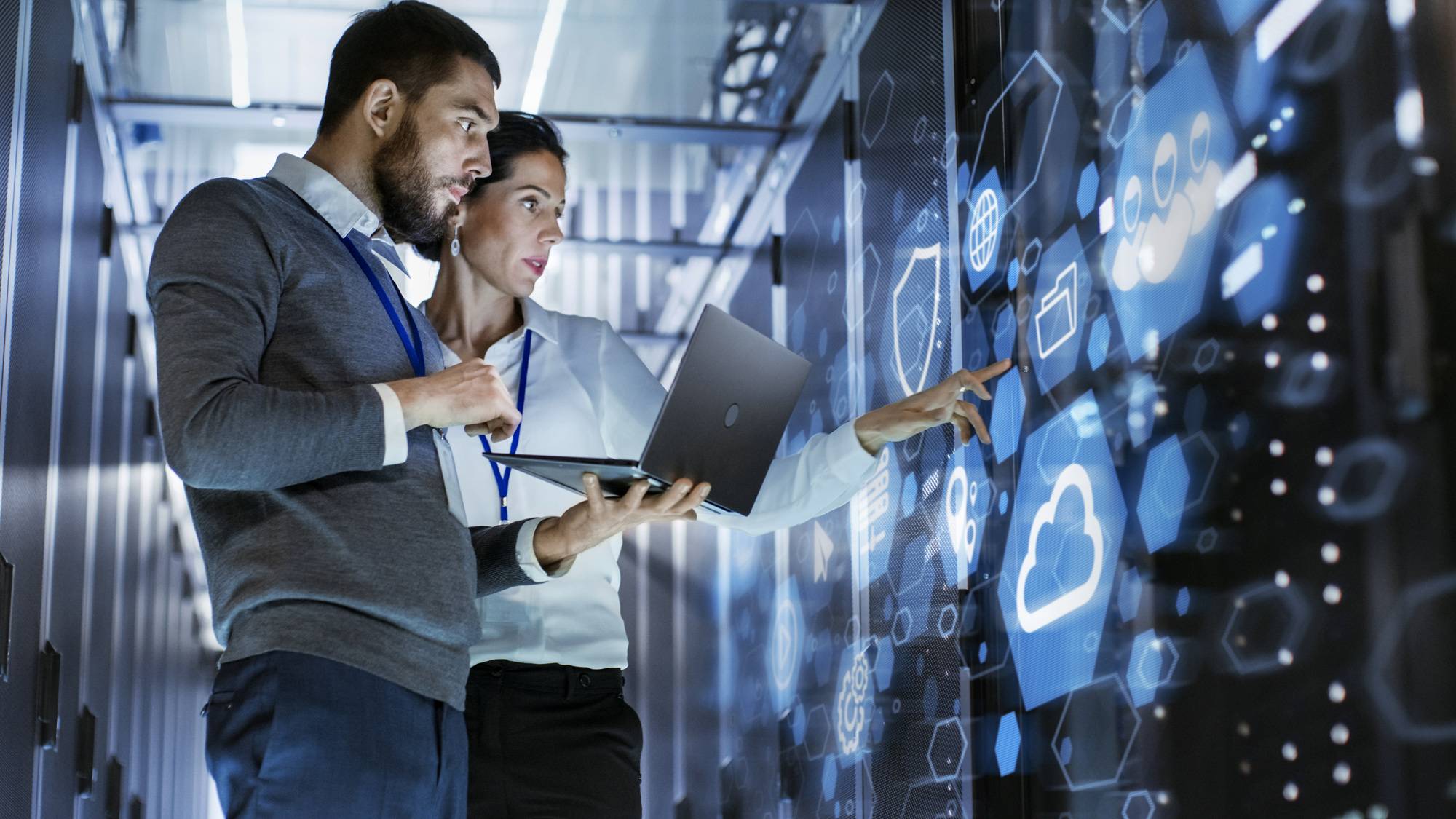 Man and woman co-workers working in data center with laptop.