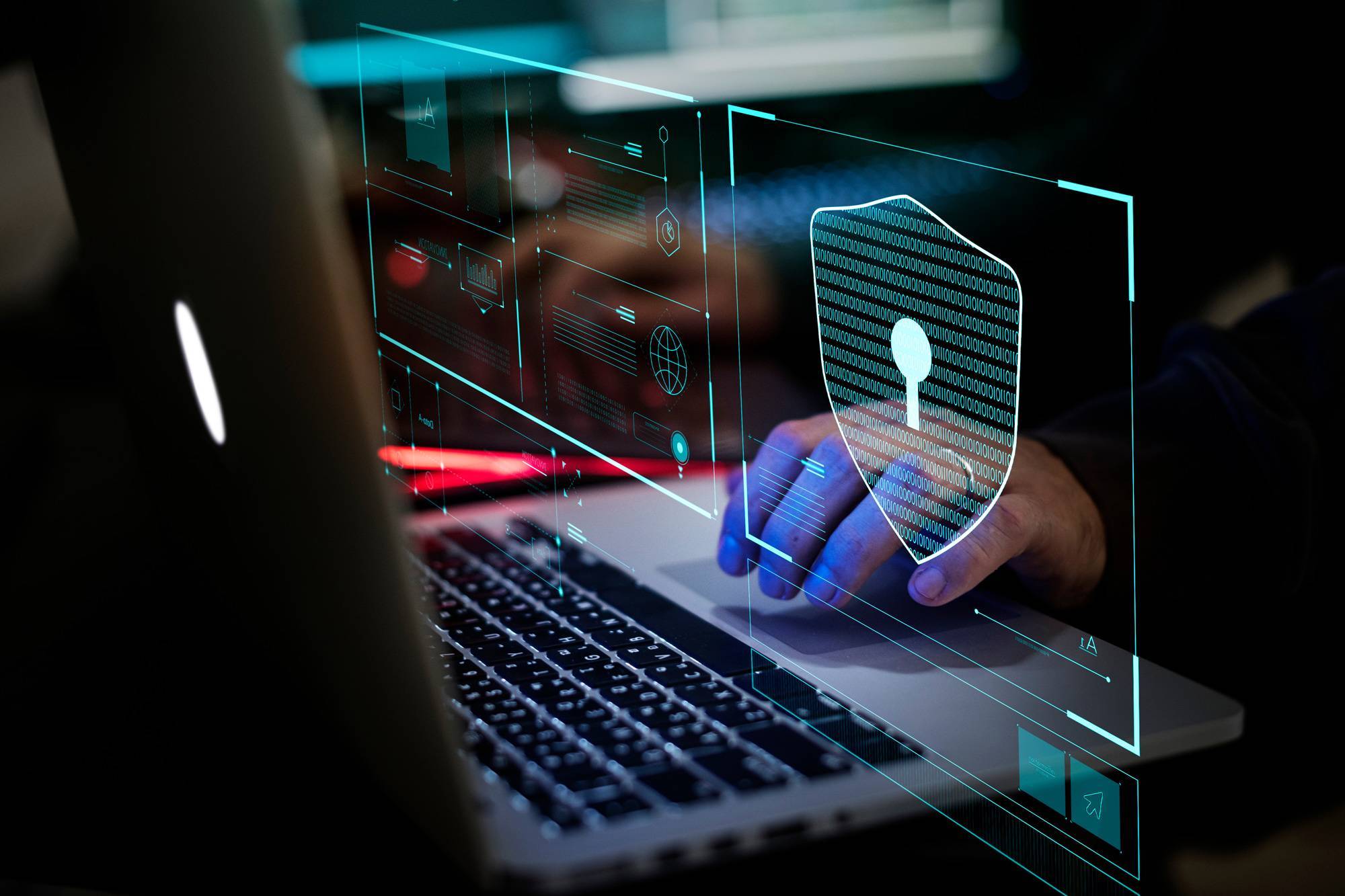 Hands typing on laptop with cyber security floating graphics.