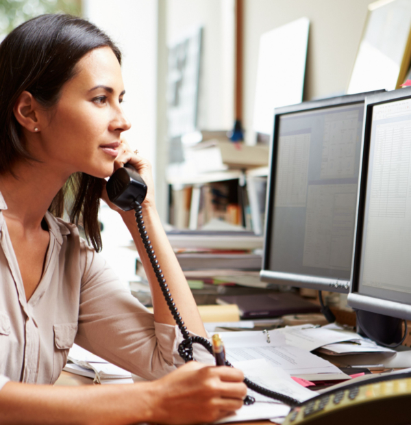 a woman sitting at a desk talking on a business phone
