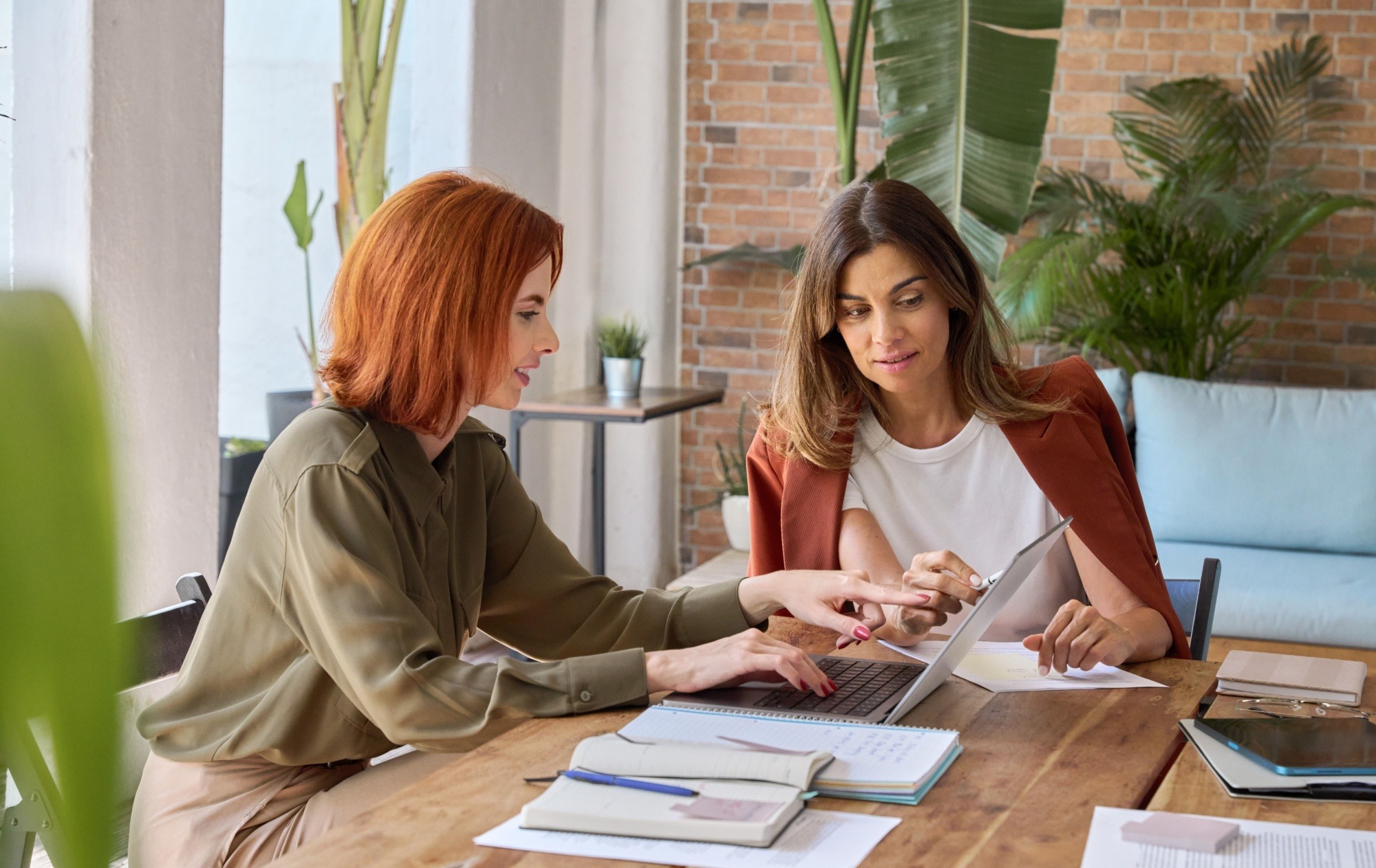 Two female entrepreneurs working together using laptop looking at computer