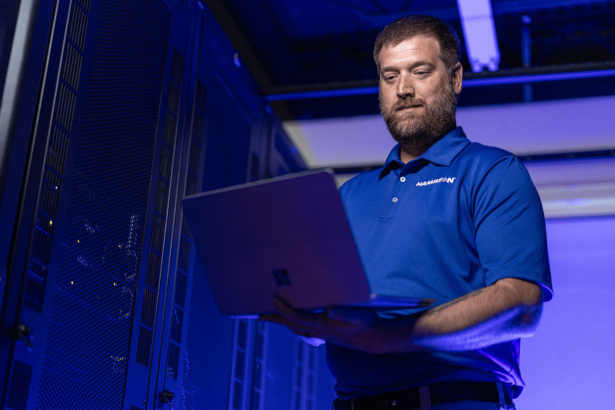 Hamilton tech working in the Hamilton data center holding laptop