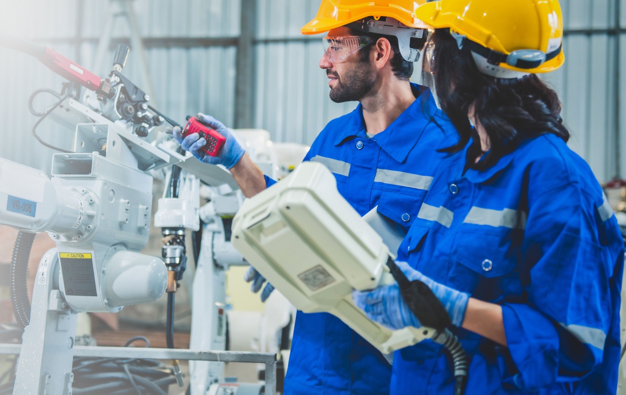 Engineers use computer controller robotic arm for welding steel in steel factory workshop.