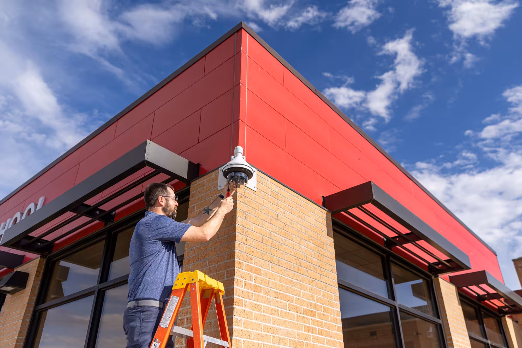 Hamilton tech installing a security camera at a school
