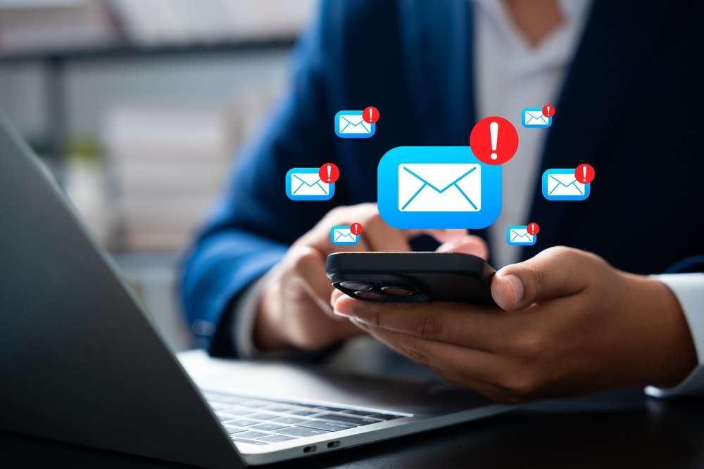 Businessman,Receive,Multiple,Scam,Email,Alerts,On,Smartphone,While,Multitasking