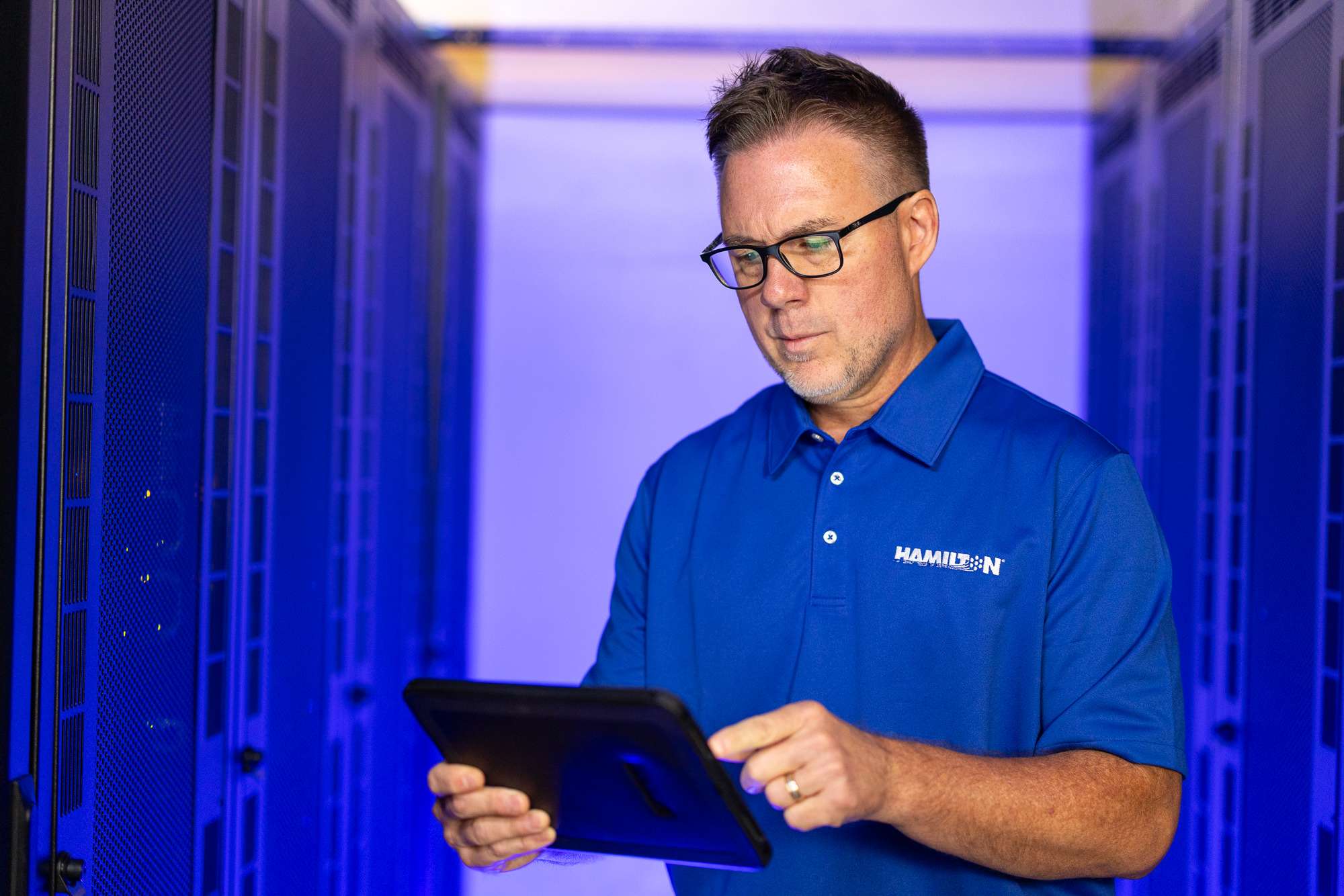Hamilton Tech standing in the Hamilton Data Center looking at an Ipad