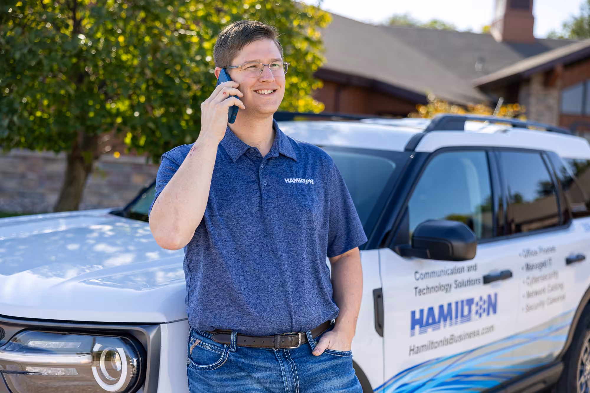 Hamilton sales man talking on the phone leaning agains a hamilton ford bronco